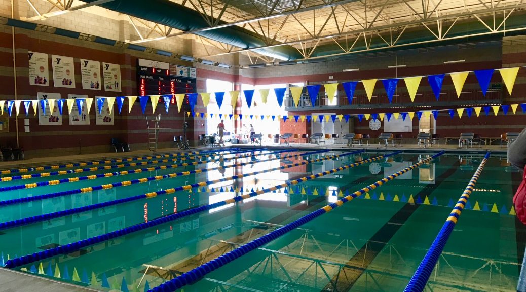Indoor wim pool with five lanes and yellow and blue flags.