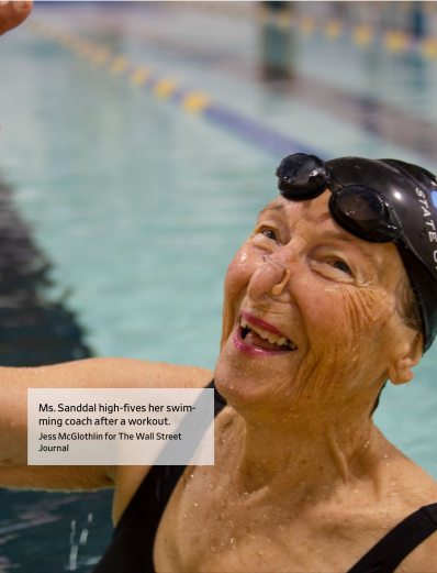 Charlotte Sandall, a white older women smiles after a swim. She wears goggles on her forehead and a nose clip.